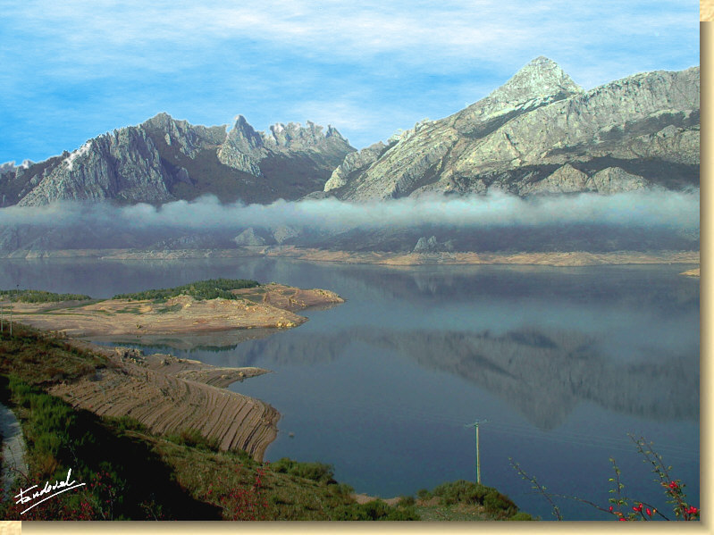 View of the reservoir of Riaño with Yordas peak in the background. A dash of fog extends through the valley.